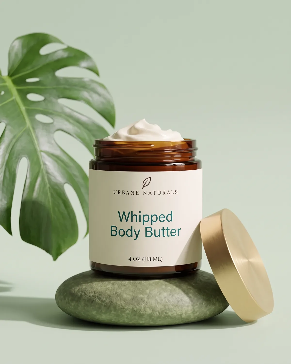 Amber glass jar of Whipped Body Butter with a gold lid on a mossy stone
